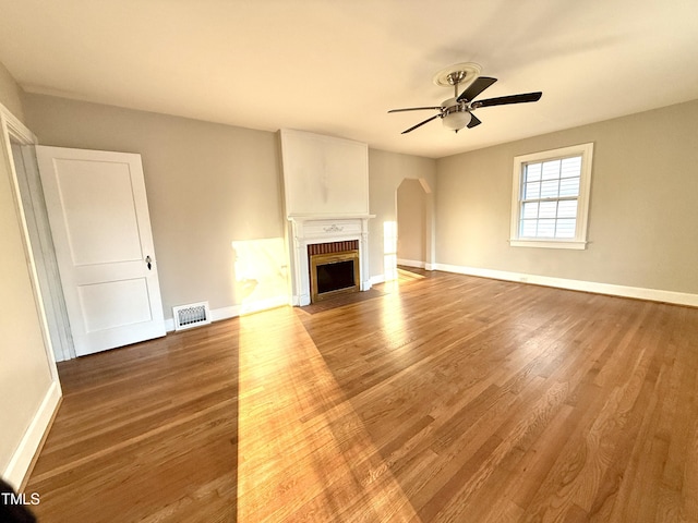 unfurnished living room with visible vents, a fireplace with flush hearth, baseboards, and wood finished floors