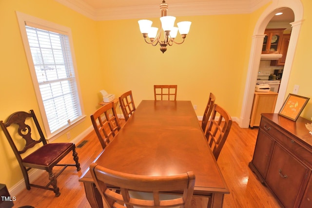 dining area featuring crown molding, visible vents, an inviting chandelier, light wood-style floors, and baseboards