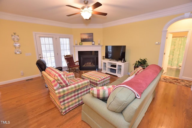living area with ornamental molding, baseboards, a fireplace, and light wood finished floors