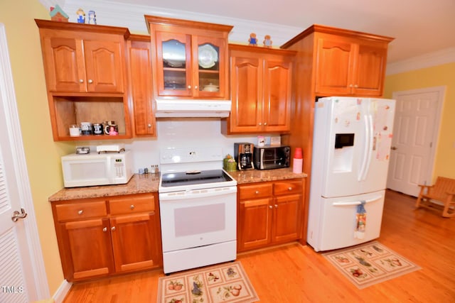 kitchen featuring white appliances, brown cabinetry, ornamental molding, light wood-type flooring, and under cabinet range hood