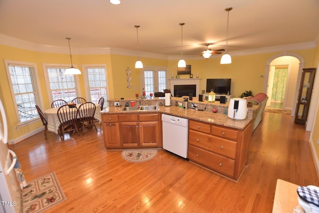 kitchen featuring open floor plan, decorative light fixtures, light stone countertops, white dishwasher, and a sink