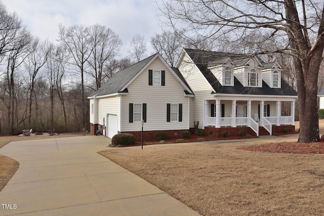 new england style home featuring a front lawn, a porch, and concrete driveway