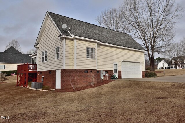 back of house with roof with shingles, a yard, central AC unit, a garage, and driveway