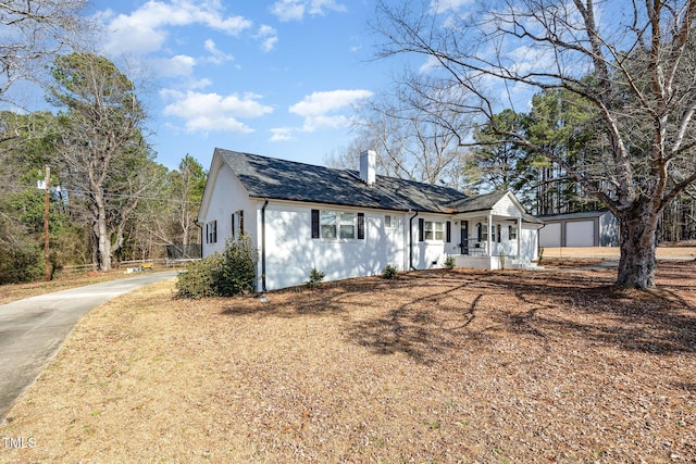 view of front of property featuring a porch, an outbuilding, a chimney, and stucco siding