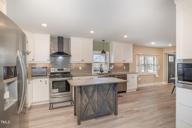 kitchen with light wood-style flooring, a sink, white cabinetry, appliances with stainless steel finishes, and wall chimney exhaust hood