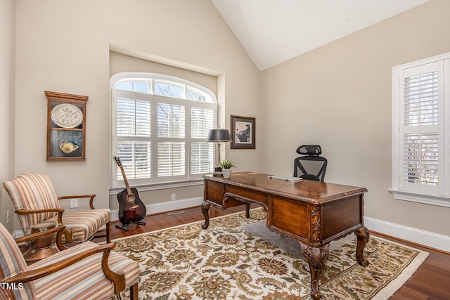 office area featuring lofted ceiling, visible vents, baseboards, and wood finished floors