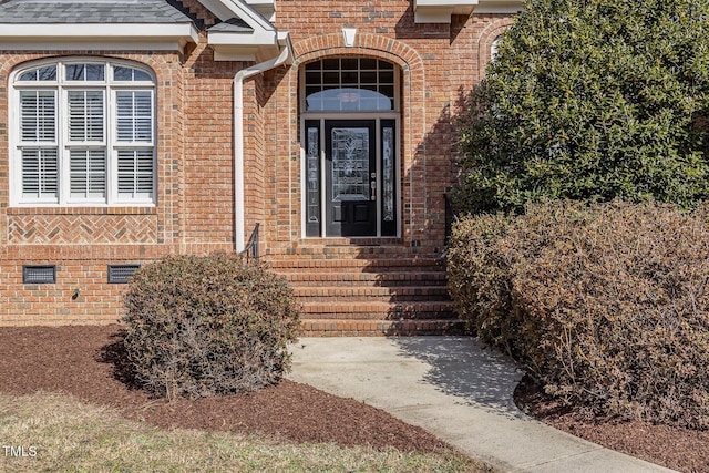 property entrance with a shingled roof, crawl space, and brick siding