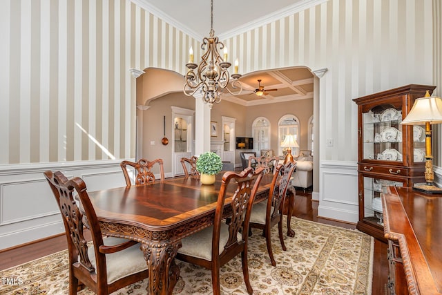 dining room with ornamental molding, arched walkways, wood finished floors, and wallpapered walls