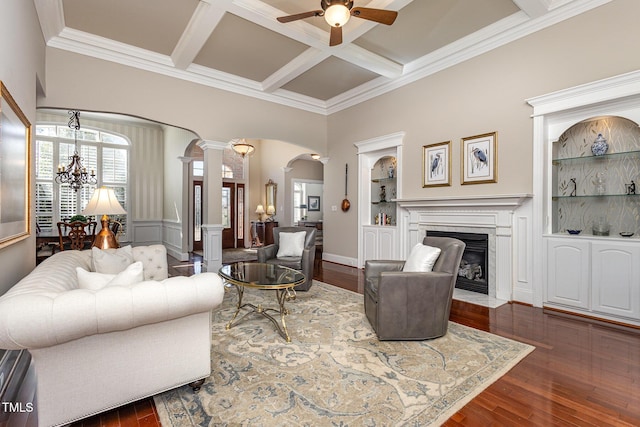 living area with built in features, arched walkways, coffered ceiling, a fireplace with flush hearth, and dark wood-style flooring