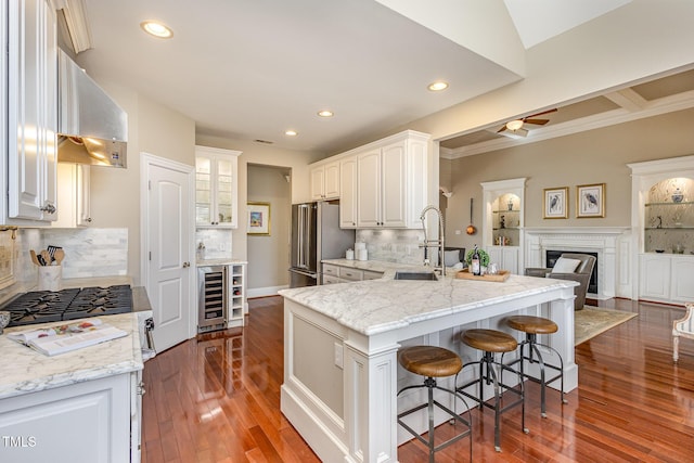 kitchen featuring high quality fridge, a breakfast bar area, wine cooler, a sink, and range hood