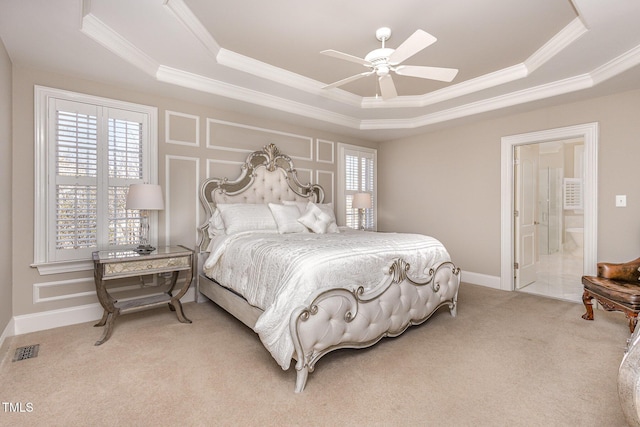 bedroom with visible vents, a raised ceiling, light colored carpet, ensuite bathroom, and crown molding