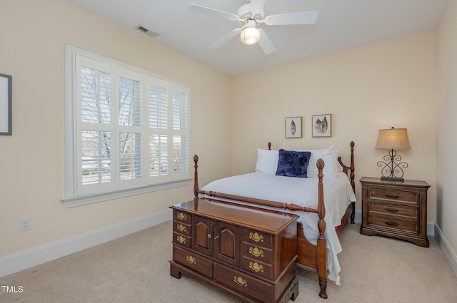 bedroom with light carpet, ceiling fan, visible vents, and baseboards