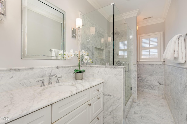 bathroom with wainscoting, ornamental molding, vanity, a shower stall, and tile walls