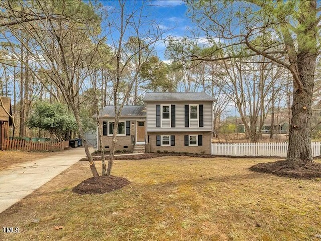 split level home featuring crawl space, brick siding, fence, and concrete driveway