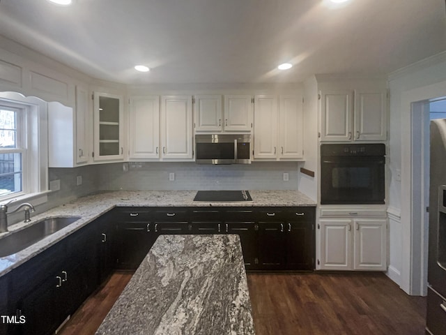 kitchen featuring glass insert cabinets, dark cabinets, black appliances, white cabinetry, and a sink