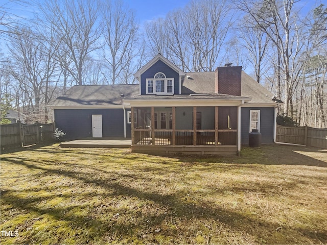 back of property featuring a fenced backyard, a sunroom, a yard, roof with shingles, and a chimney