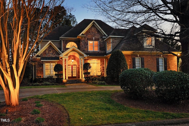 view of front of home featuring stone siding, curved driveway, and a front yard