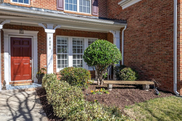 entrance to property featuring covered porch and brick siding