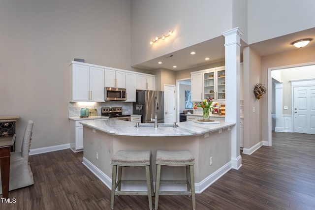 kitchen featuring glass insert cabinets, a high ceiling, white cabinetry, and stainless steel appliances