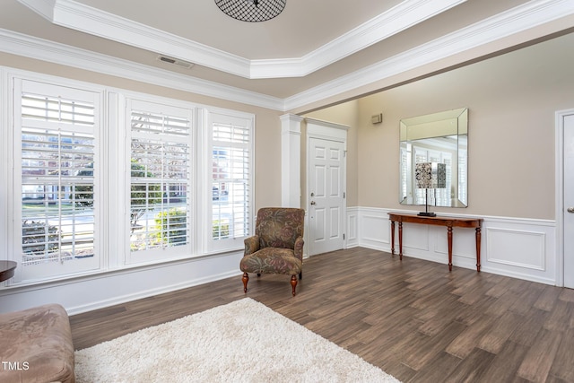 living area featuring a wainscoted wall, decorative columns, visible vents, ornamental molding, and wood finished floors