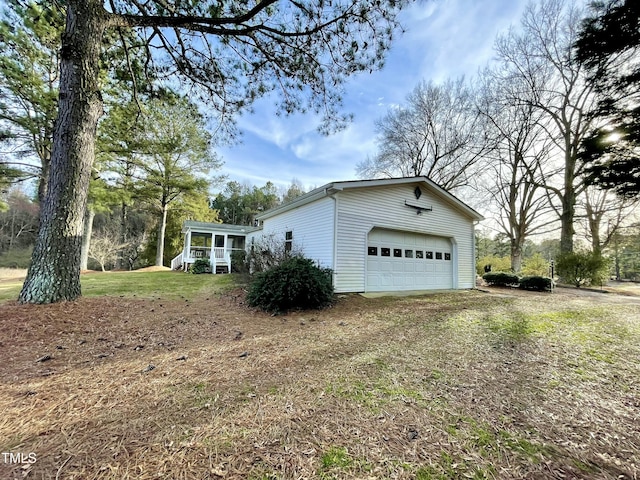 view of side of home featuring a garage, a sunroom, driveway, and a lawn