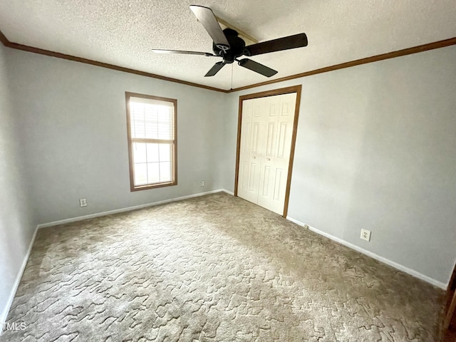 unfurnished bedroom with carpet, a closet, ornamental molding, a textured ceiling, and baseboards