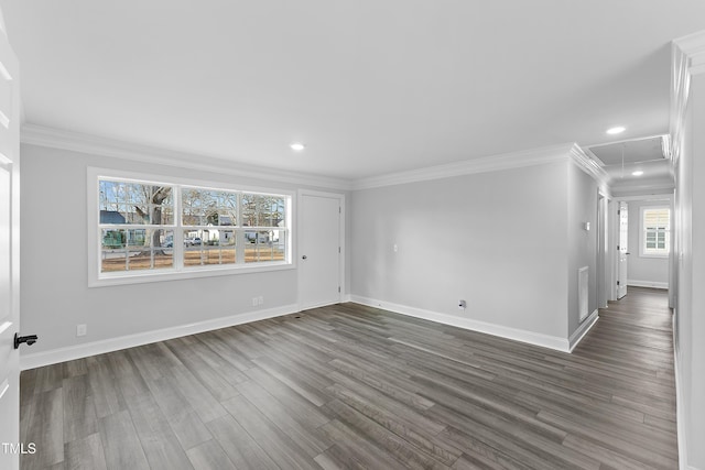 unfurnished room featuring dark wood finished floors, attic access, crown molding, and baseboards