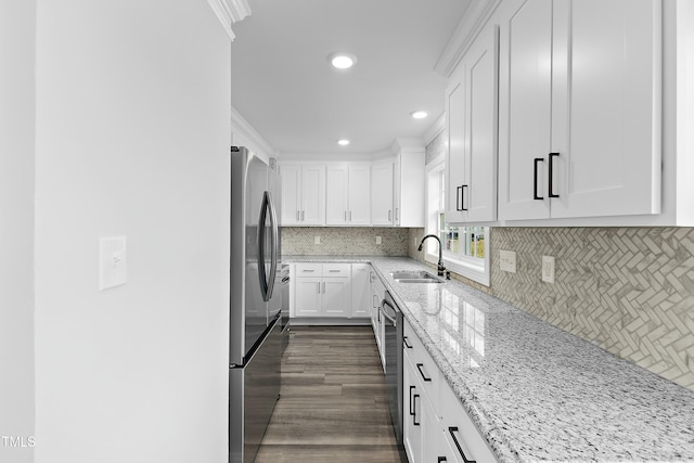 kitchen with white cabinetry, light stone countertops, appliances with stainless steel finishes, and a sink