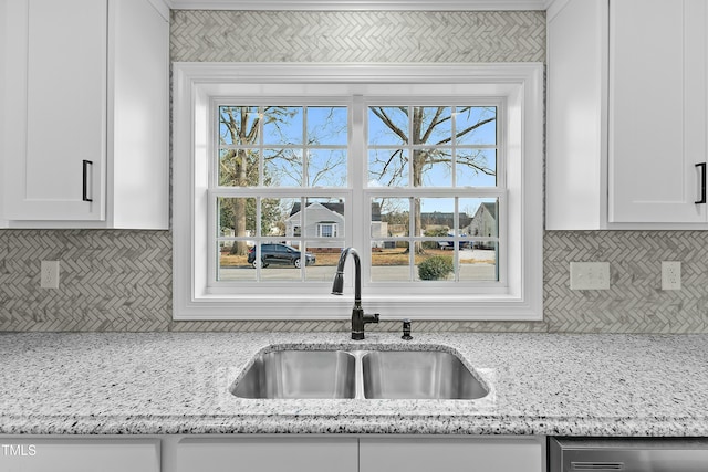 kitchen featuring light stone counters, backsplash, and a sink