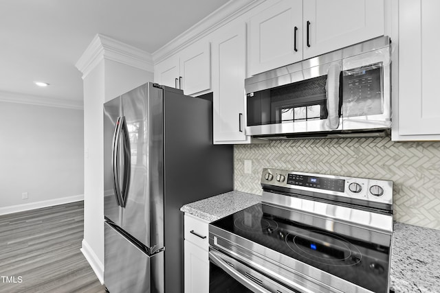 kitchen with baseboards, ornamental molding, stainless steel appliances, white cabinets, and backsplash