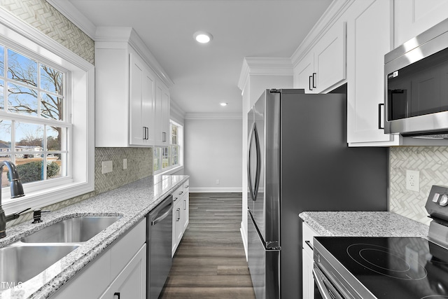 kitchen with a sink, appliances with stainless steel finishes, ornamental molding, and white cabinets