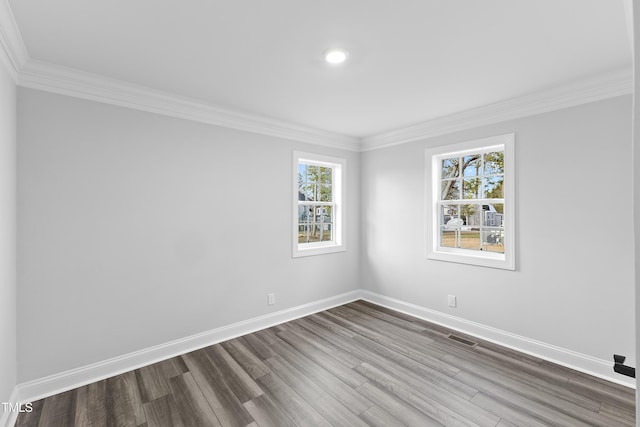 empty room featuring visible vents, baseboards, dark wood-type flooring, and ornamental molding