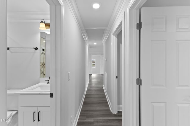 hallway featuring crown molding, baseboards, attic access, dark wood-style floors, and a sink