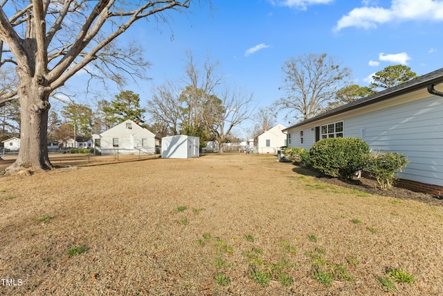 view of yard with an outdoor structure, a storage unit, fence, and a residential view