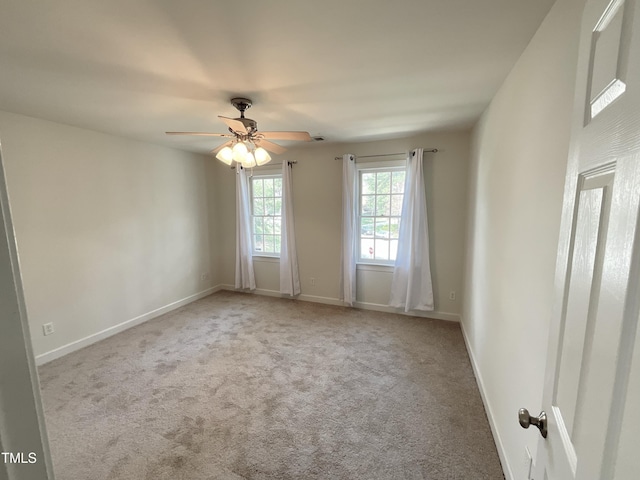 carpeted empty room with a ceiling fan and baseboards