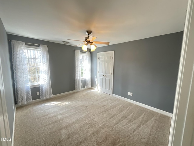 carpeted spare room with baseboards and ceiling fan