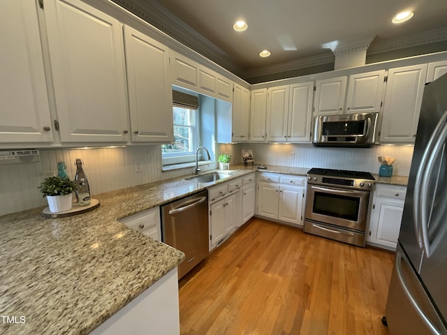 kitchen with a sink, stainless steel appliances, decorative backsplash, and white cabinetry