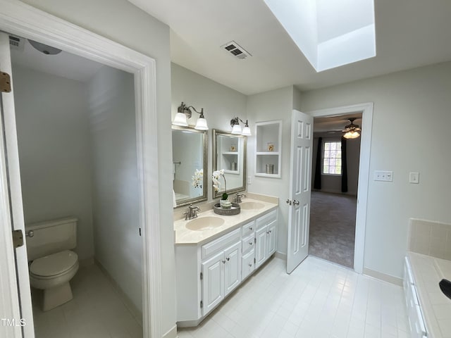 bathroom featuring visible vents, toilet, double vanity, a skylight, and a sink