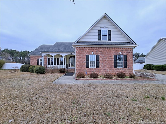 traditional-style home with covered porch, roof with shingles, and brick siding