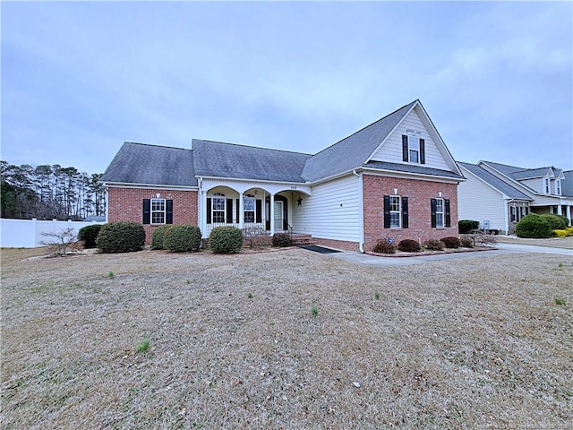 view of front facade featuring covered porch, brick siding, and fence