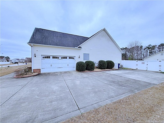 view of home's exterior with driveway, a garage, a shingled roof, a gate, and fence