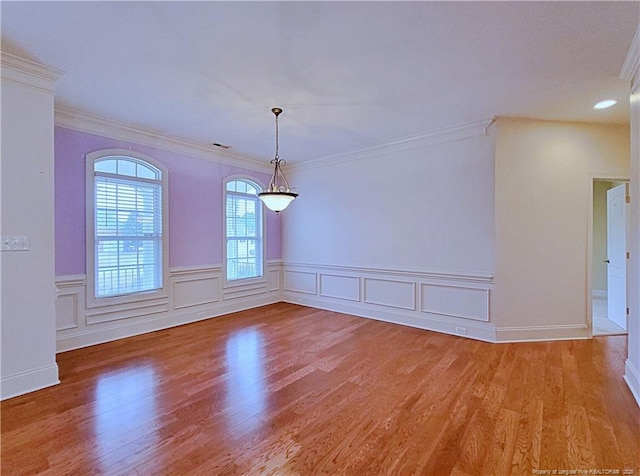 unfurnished dining area featuring ornamental molding, a wainscoted wall, visible vents, and light wood finished floors