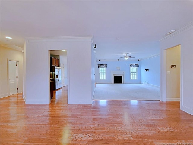 unfurnished living room with a fireplace, a ceiling fan, baseboards, light wood-style floors, and crown molding