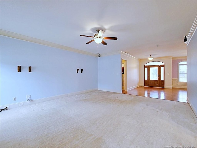 unfurnished living room featuring ceiling fan, baseboards, and crown molding