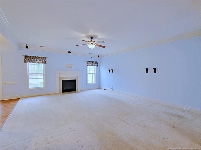 unfurnished living room with ornamental molding, a ceiling fan, a high end fireplace, and baseboards