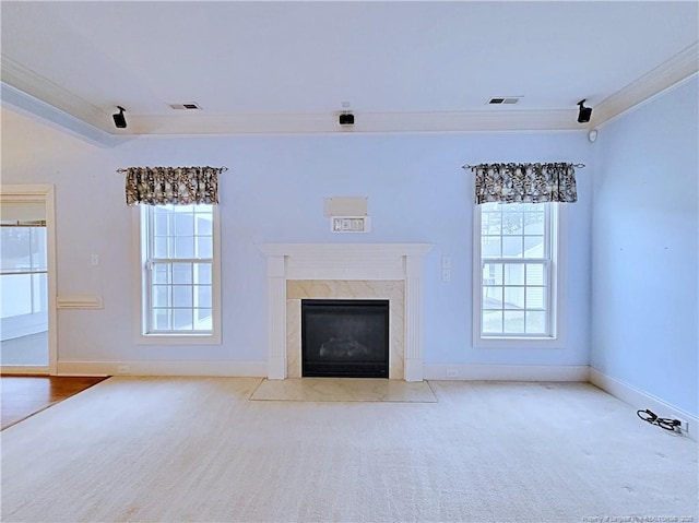 unfurnished living room with baseboards, a premium fireplace, visible vents, and crown molding