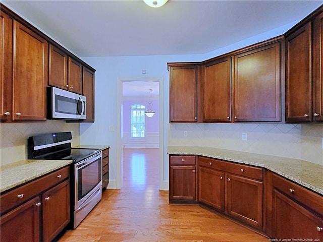 kitchen with light stone counters, light wood-style flooring, baseboards, appliances with stainless steel finishes, and decorative backsplash