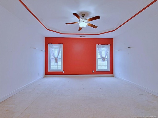 empty room with baseboards, a tray ceiling, ceiling fan, and ornamental molding