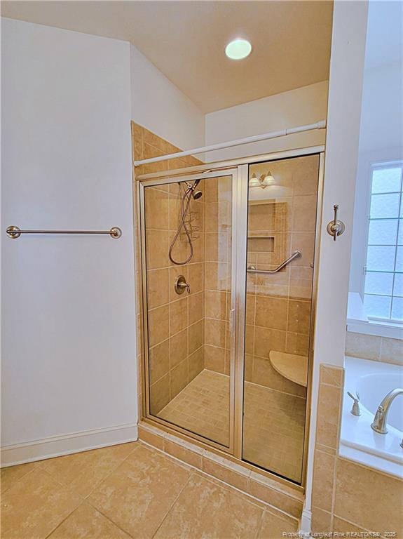 bathroom with a shower stall, baseboards, a bath, and tile patterned floors