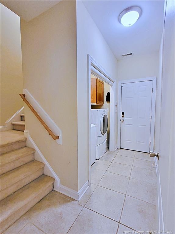 laundry area with light tile patterned flooring, visible vents, baseboards, washer and dryer, and cabinet space